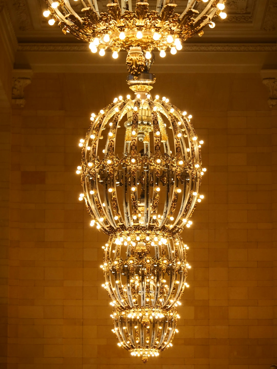 An ornate, multi-tiered golden chandelier with many lights.