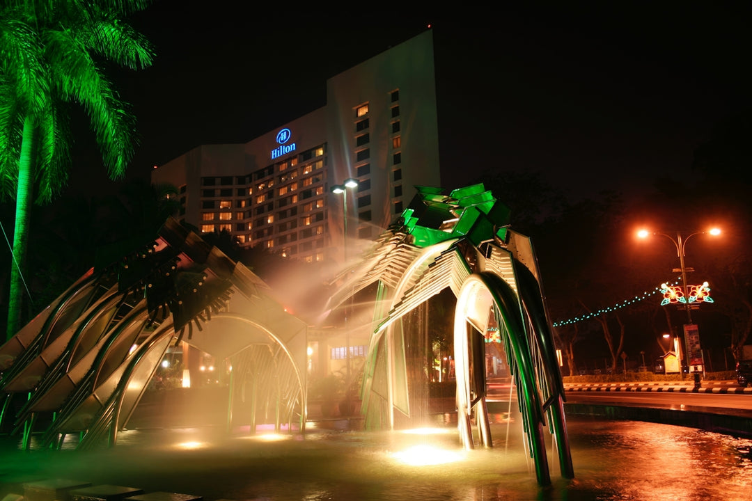 A modern hotel at night with a lit fountain