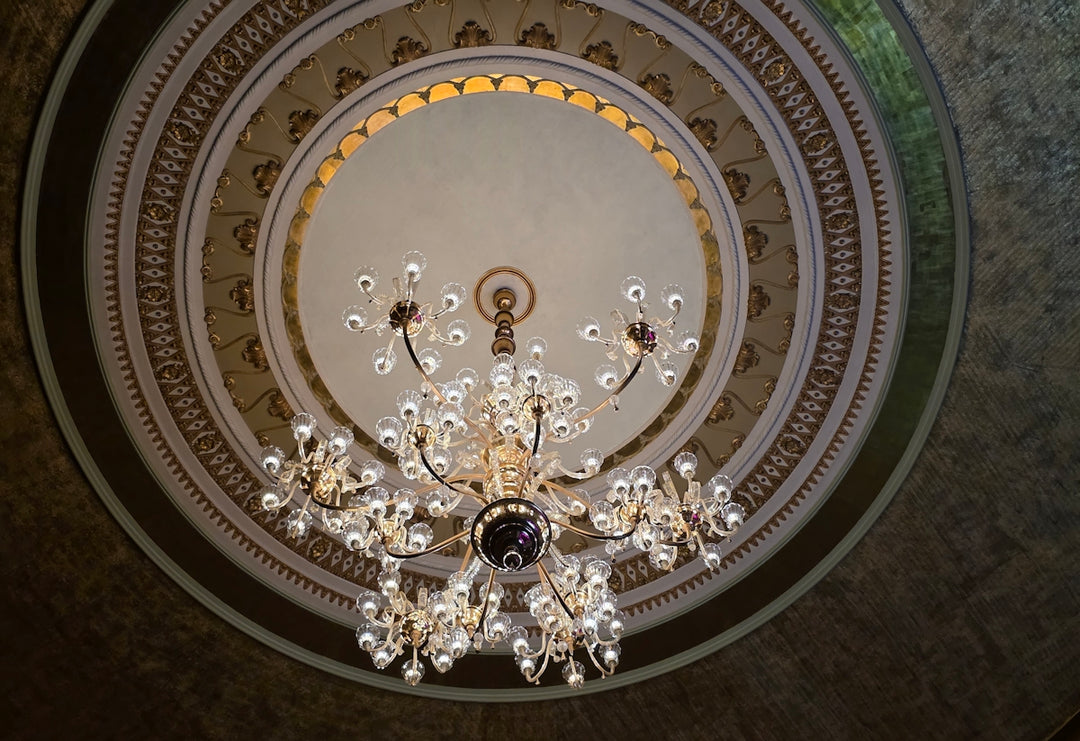 A grand ornate chandelier hangs from a decorative ceiling.