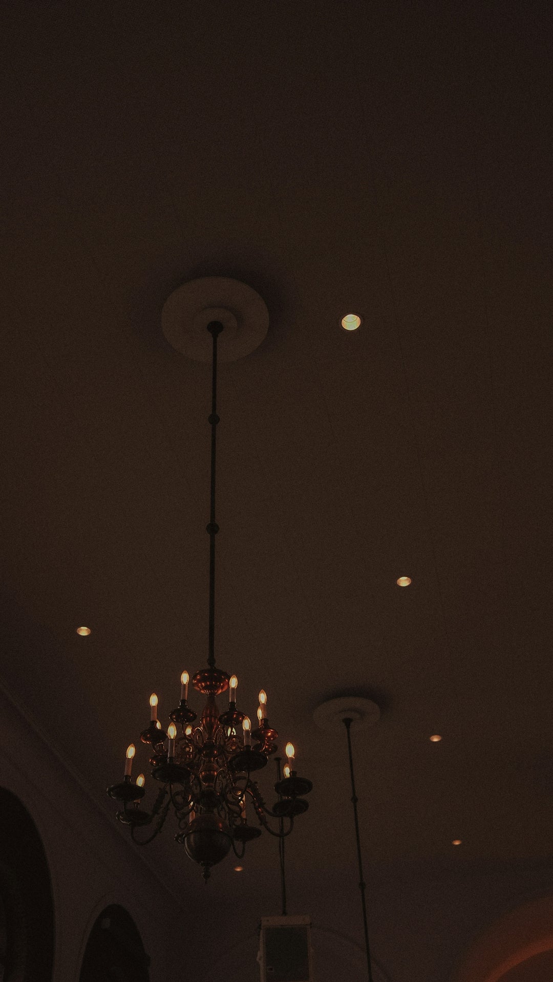 A vintage chandelier hanging from a dark ceiling.
