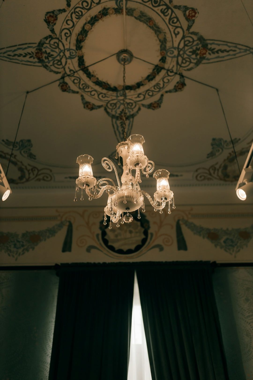 Ornate chandelier hangs from a decorated ceiling.