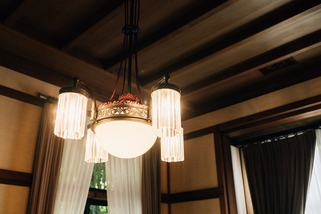 Antique chandelier hanging from wooden ceiling beams.