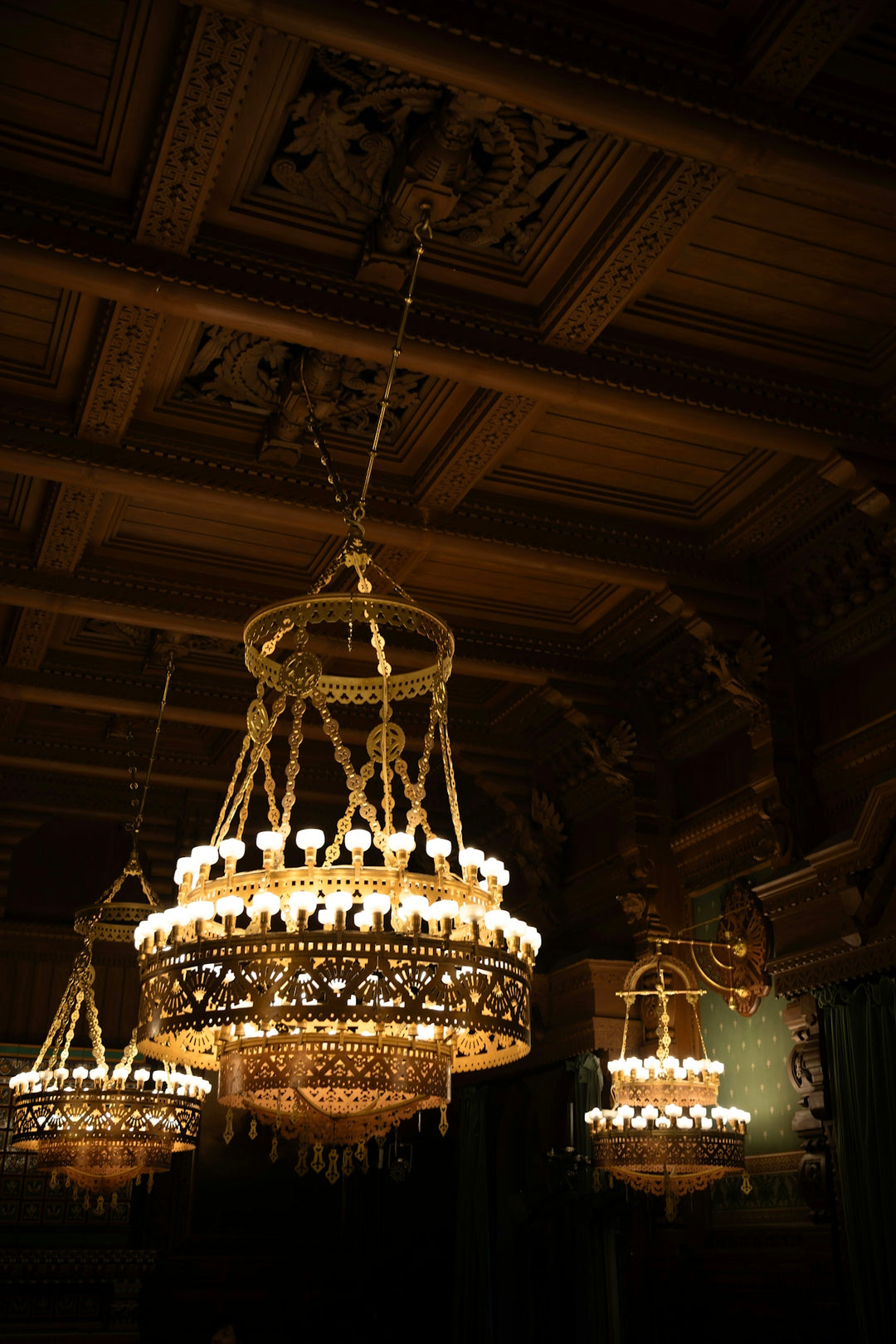 Ornate chandeliers hanging from a dark wooden ceiling