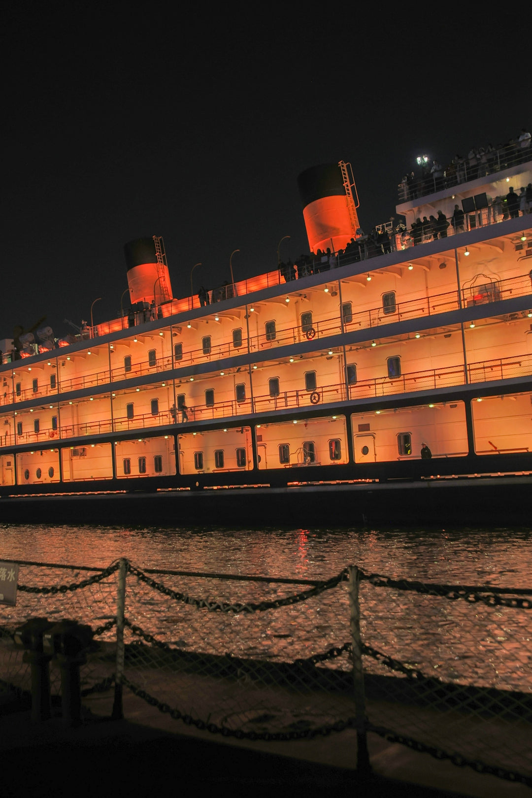 Large illuminated cruise ship docked at night.