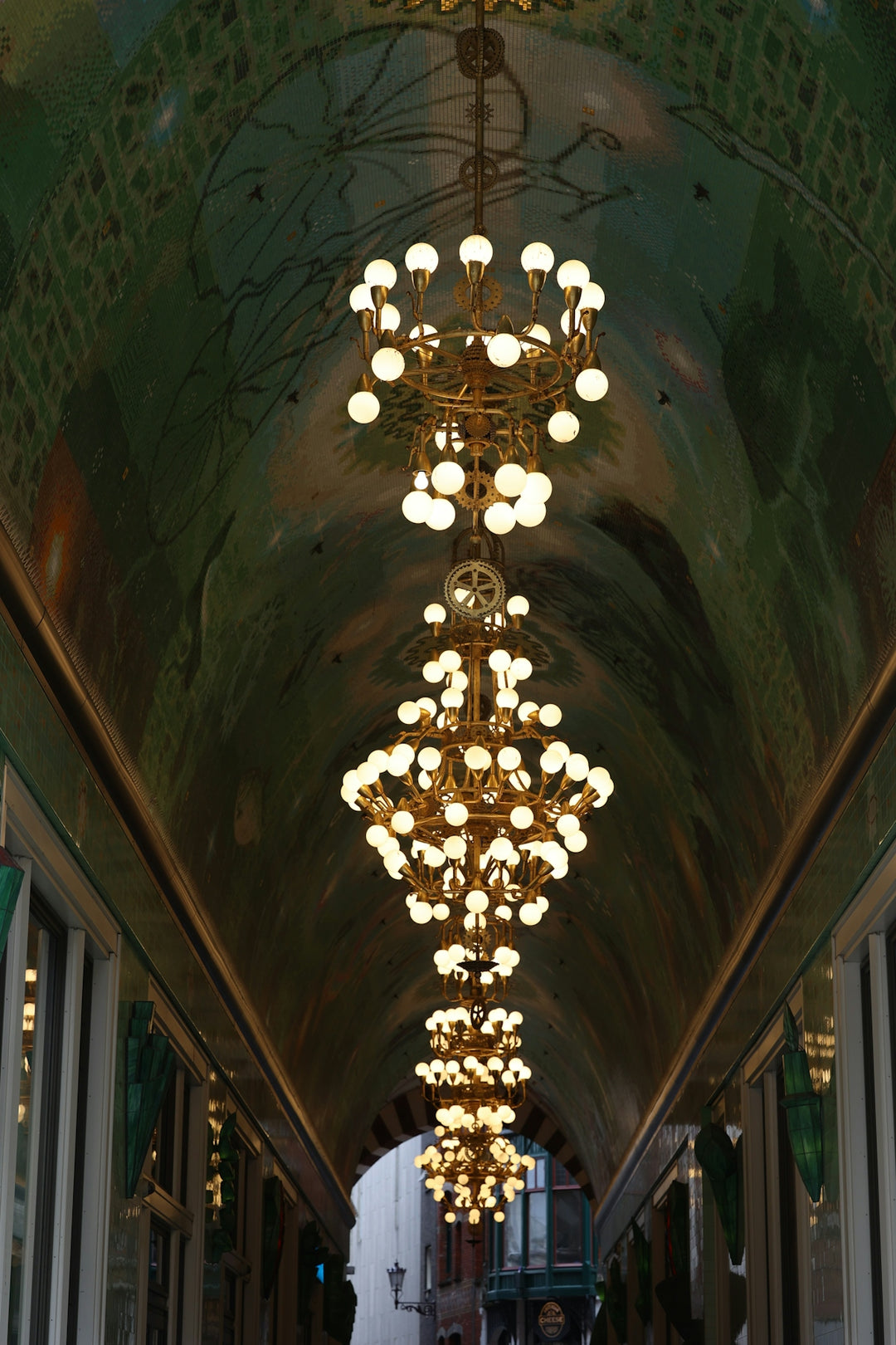 Ornate chandeliers illuminate a long, arched hallway.