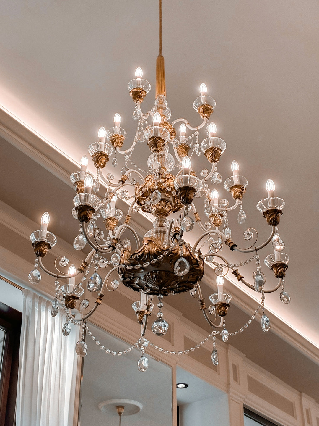 An ornate crystal chandelier hangs from a luxurious ceiling.