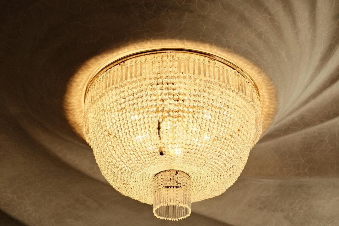 A crystal chandelier hangs from a textured ceiling, casting light