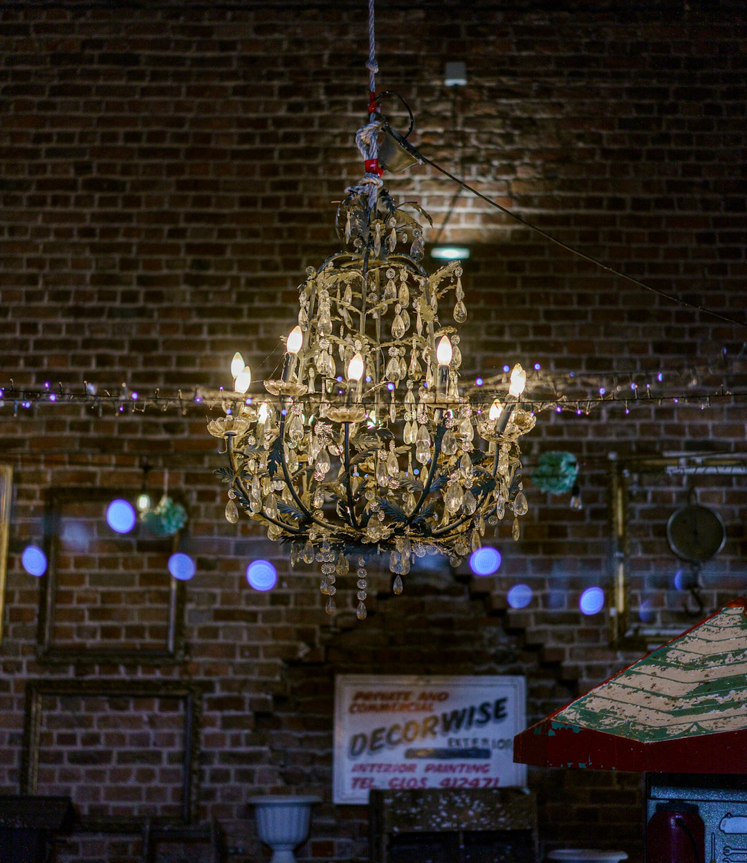 A crystal chandelier hanging in front of a rustic brick wall